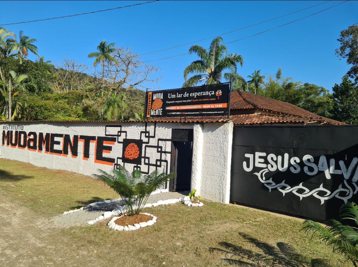 Fachada do Instituto Muda Mente, com placa e jardim.