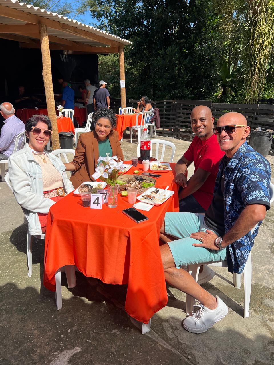 Pessoas reunidas ao redor de uma mesa laranja.