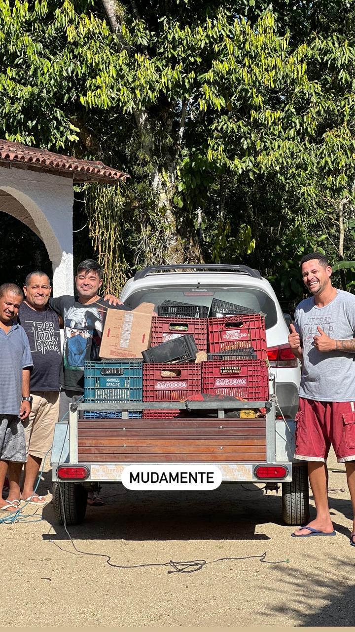 Pessoas reunidas perto de um veículo vermelho em uma área externa.