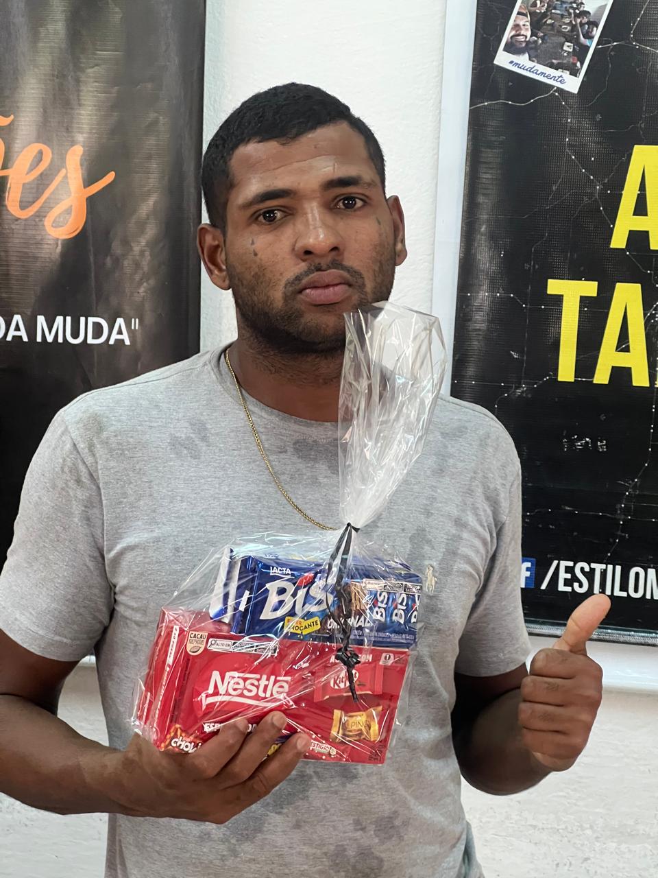 Homem segurando pequenos presentes e fazendo gesto positivo com a mão.